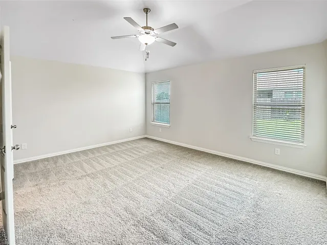 an empty room with chandelier fan and windows