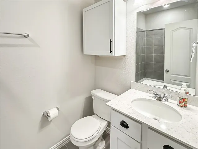 a bathroom with a granite countertop toilet sink and mirror