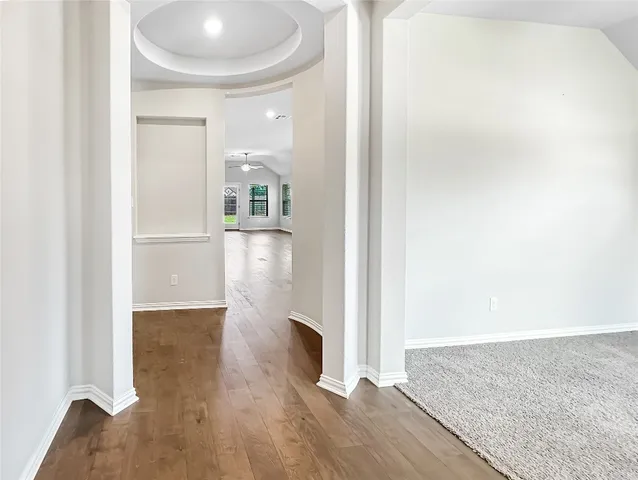 a view of a hallway with wooden floor and a bathroom