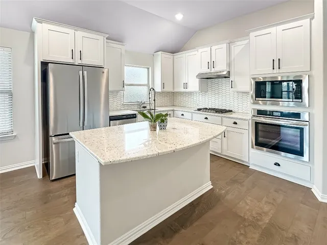 a kitchen with stainless steel appliances granite countertop a stove top oven a refrigerator and a sink