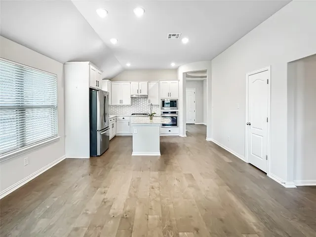 a view of kitchen view wooden floor cabinets and stainless steel appliances