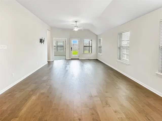a view of an empty room with a window and wooden floor