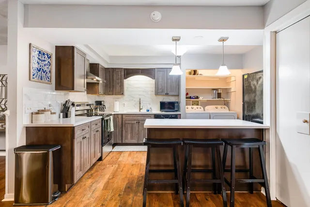 a kitchen with stainless steel appliances a table and chairs in it