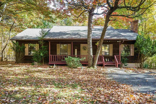 a view of a house with a small yard and a large tree