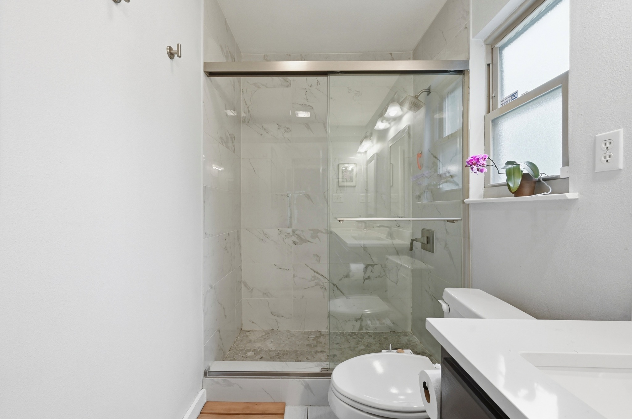 2509 Redleaf Lane Austin, TX 78745 - Photo 13 of 28 Glass-enclosed shower with white marble-style tile surround and pebbled floor