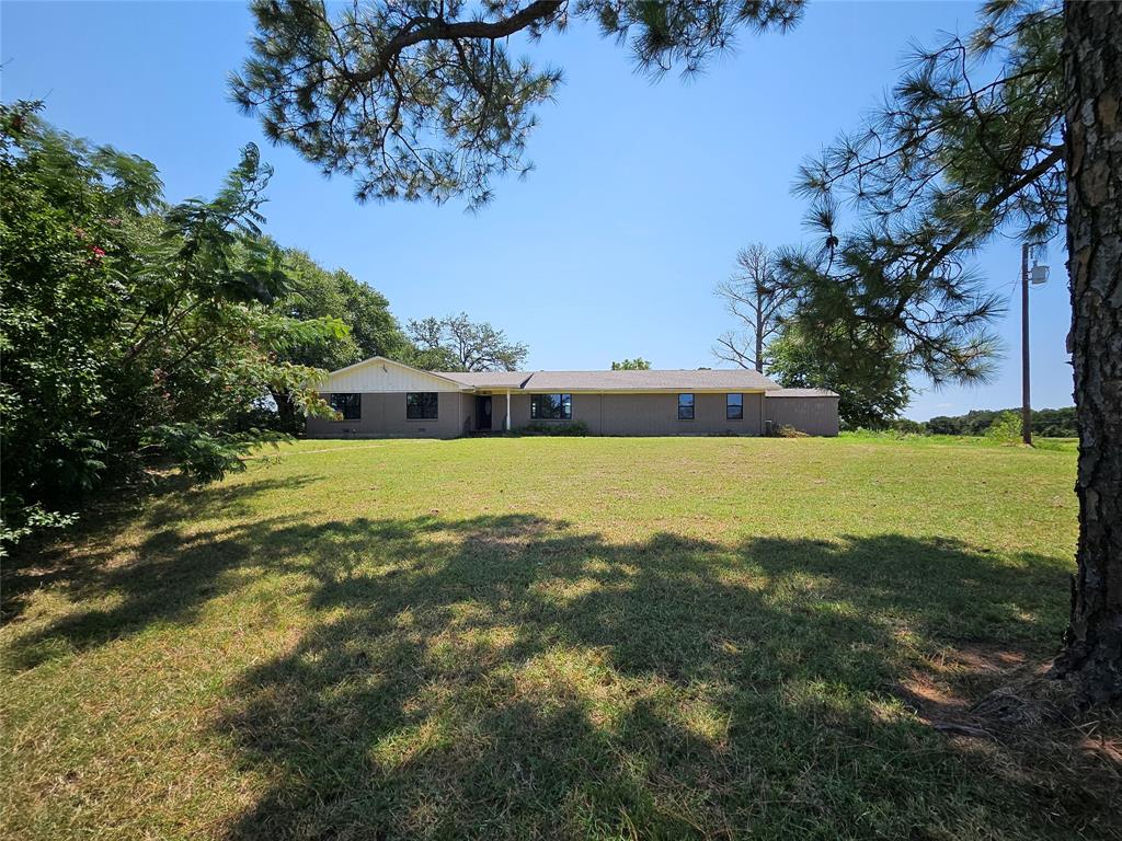 a view of a large pool with lawn chairs under an umbrella