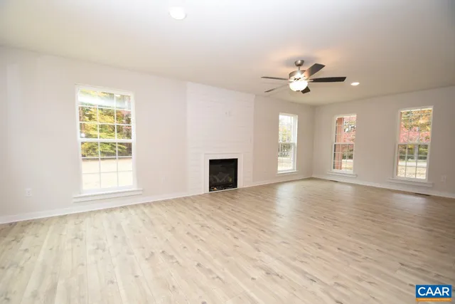 a view of an empty room with window and wooden floor