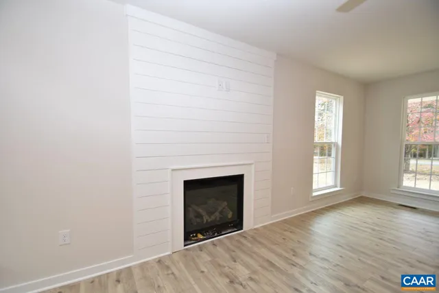an empty room with wooden floor fireplace and windows
