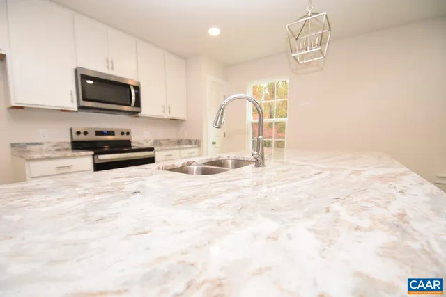 a kitchen with granite countertop a stove and a white cabinets