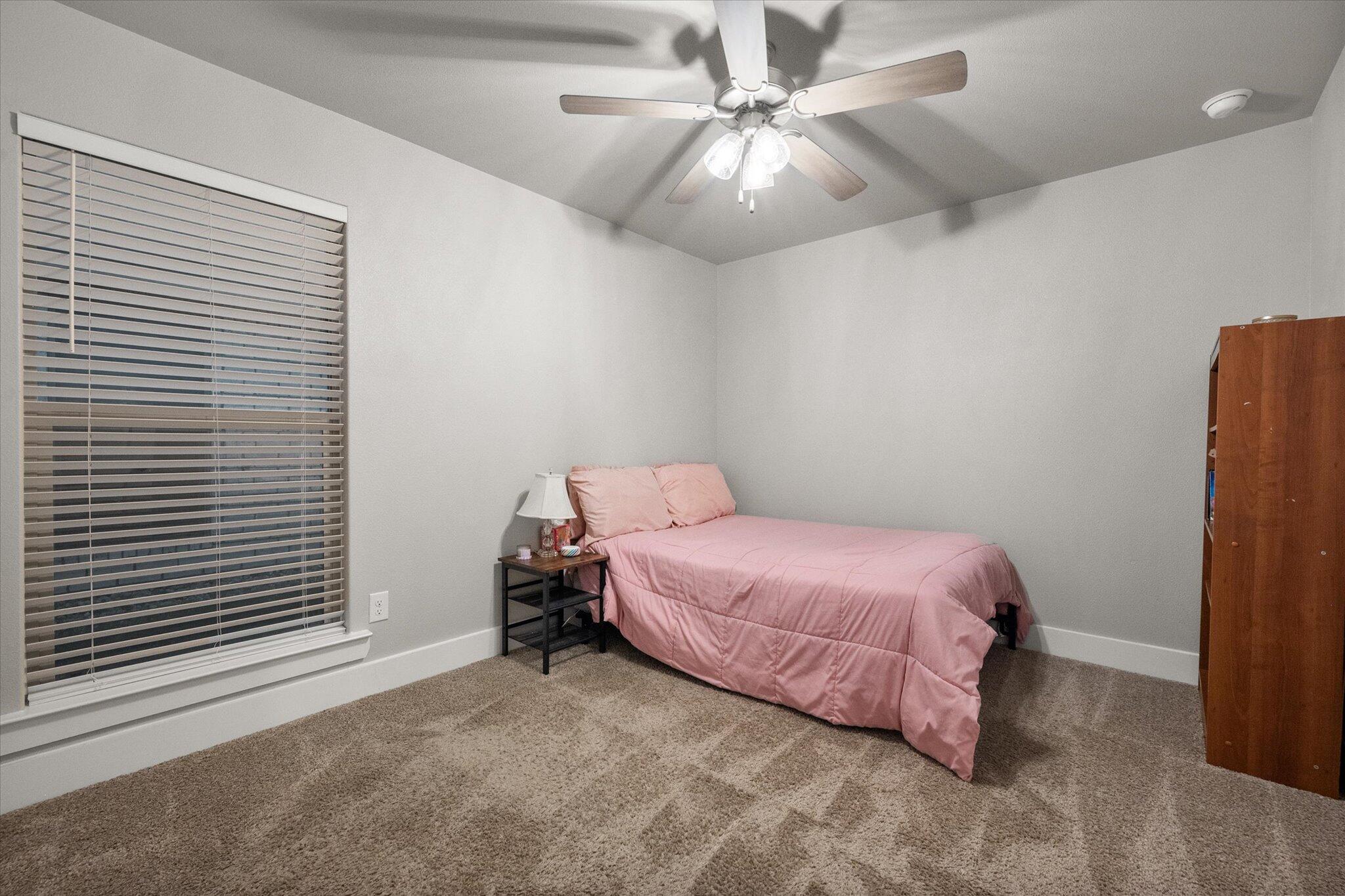 7449 31st Street Lubbock, TX 79407 - Photo 18 of 23 a bedroom with a bed and a chandelier