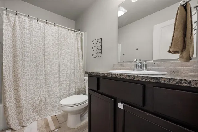 a bathroom with a granite countertop sink toilet and mirror