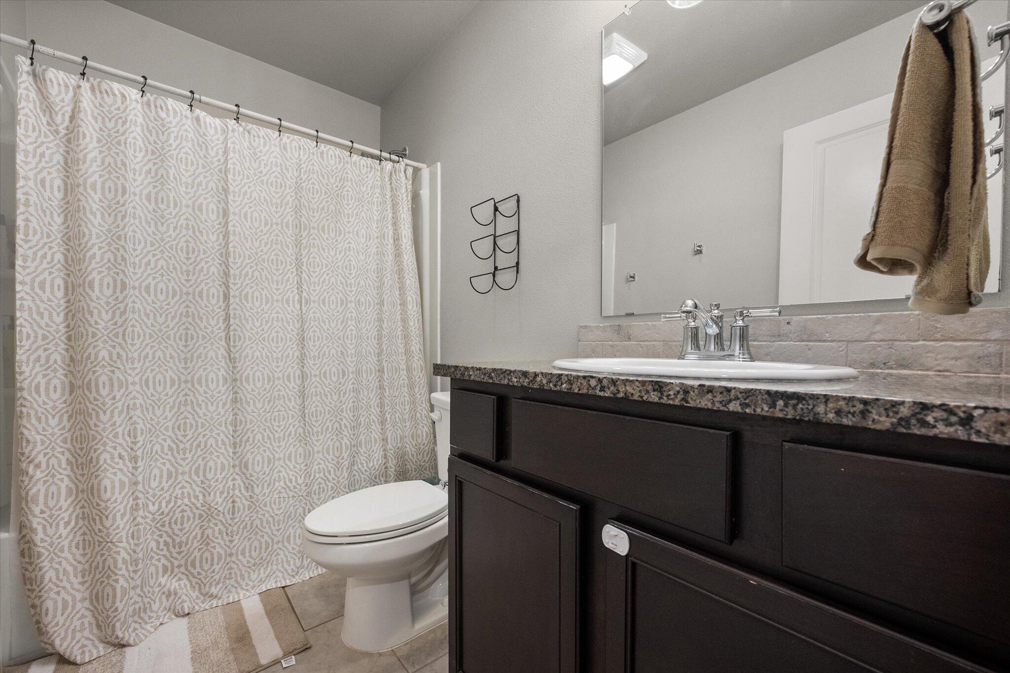 7449 31st Street Lubbock, TX 79407 - Photo 19 of 23 a bathroom with a granite countertop sink toilet and mirror