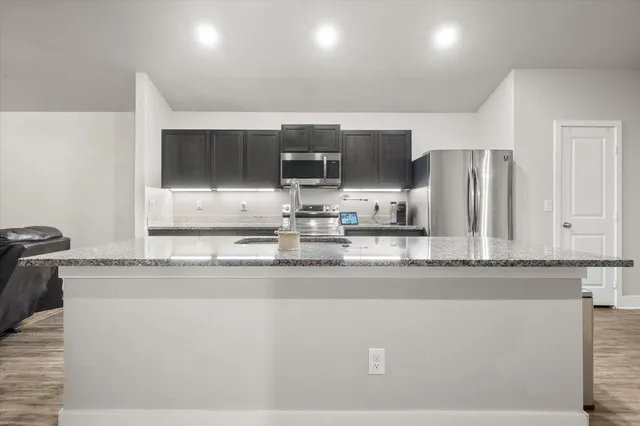 a kitchen with stainless steel appliances granite countertop a sink and a refrigerator