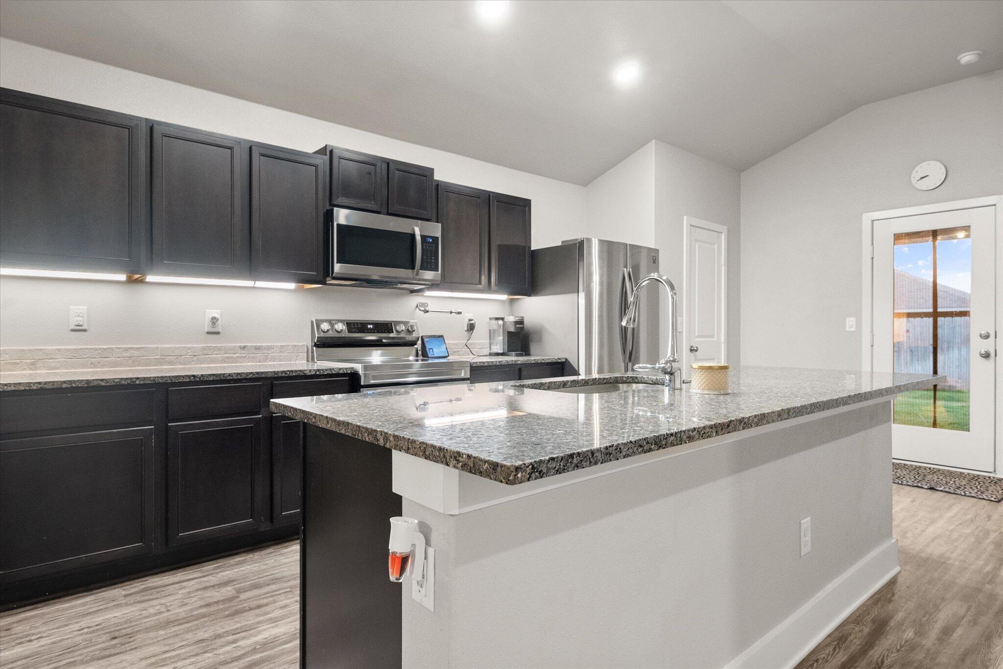 7449 31st Street Lubbock, TX 79407 - Photo 9 of 23 a kitchen with stainless steel appliances granite countertop a sink a stove and cabinets