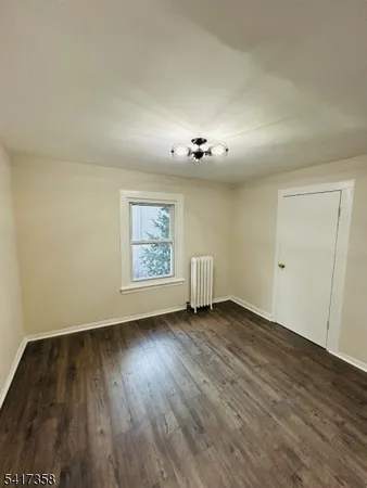 an empty room with wooden floor chandelier and windows