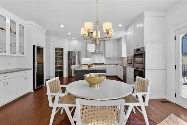 a kitchen with stainless steel appliances granite countertop a dining table chairs and a refrigerator