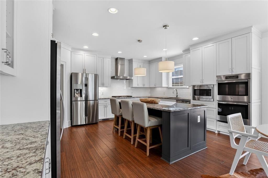 1311 Conway Road Decatur, GA 30030 - Photo 22 of 49 a kitchen with stainless steel appliances granite countertop a refrigerator a stove top oven a sink dishwasher and a dining table with wooden floor