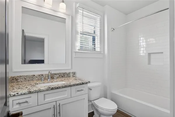 a bathroom with a granite countertop toilet a sink and a bathtub