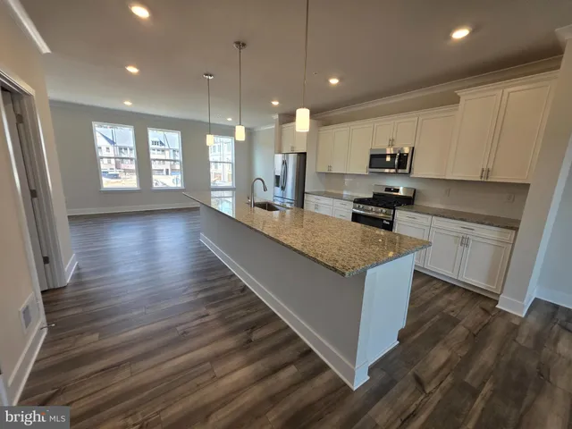 a large kitchen with stainless steel appliances granite countertop a stove a sink a refrigerator and a wooden floors