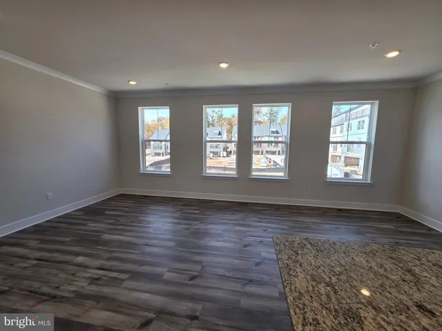 a view of an empty room with wooden floor and window