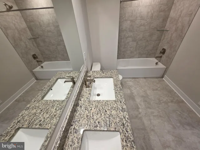 a bathroom with a granite countertop sink a toilet and bathtub