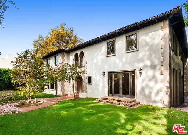 a view of a white house with a big yard and potted plants