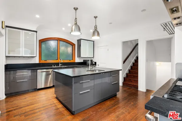 a kitchen with stainless steel appliances granite countertop a sink a stove and a wooden floor