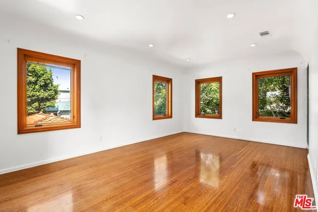 a view of an empty room with window and wooden floor