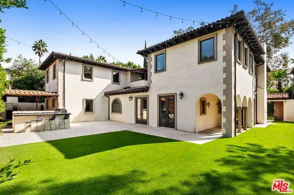 a view of a white house with a big yard potted plants and a table