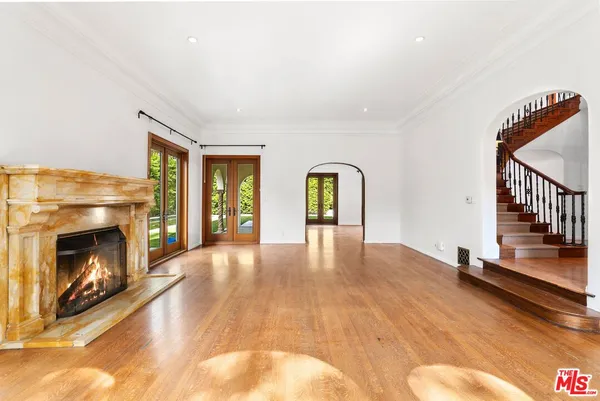 a view of an empty room with wooden floor fireplace and a window