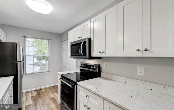 a kitchen with granite countertop white cabinets and black appliances