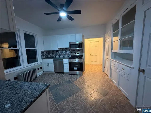 a kitchen with stainless steel appliances granite countertop a stove top oven a sink and a refrigerator