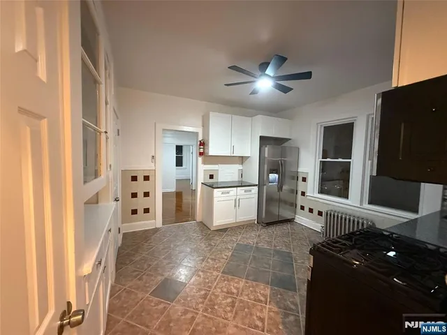 a kitchen with white cabinets and refrigerator