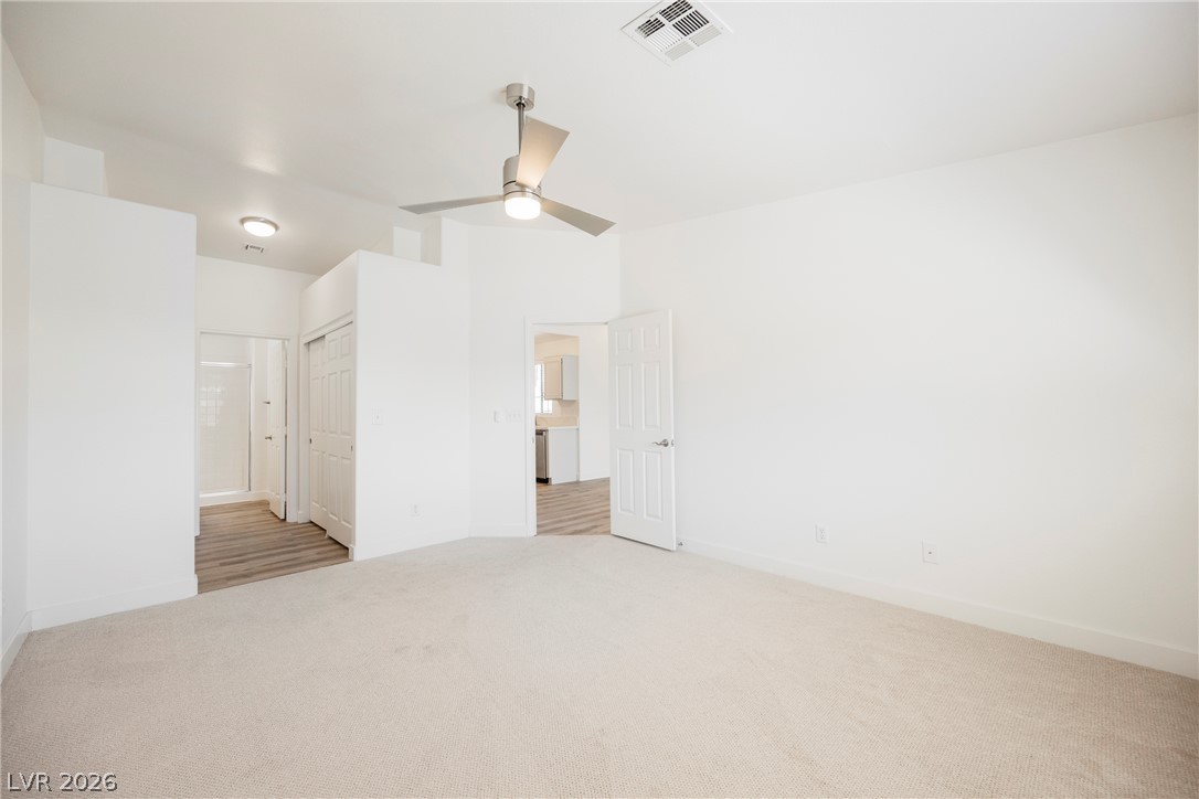 112 Iridescent Street Henderson, NV 89012 - Photo 12 of 24 A spacious, airy primary bedroom offers carpeted flooring and a modern ceiling fan.