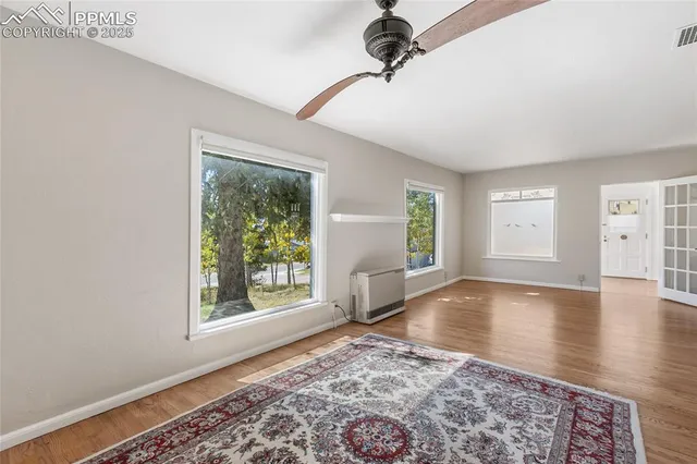 a view of an empty room with a window and wooden floor