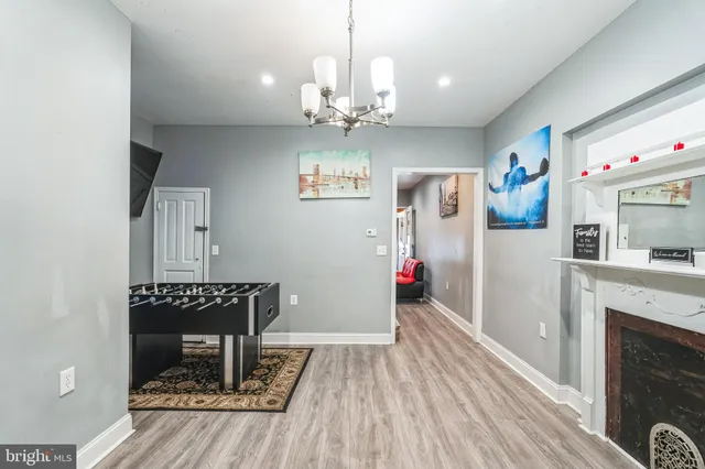 a view of a livingroom with a fireplace a chandelier and wooden floor