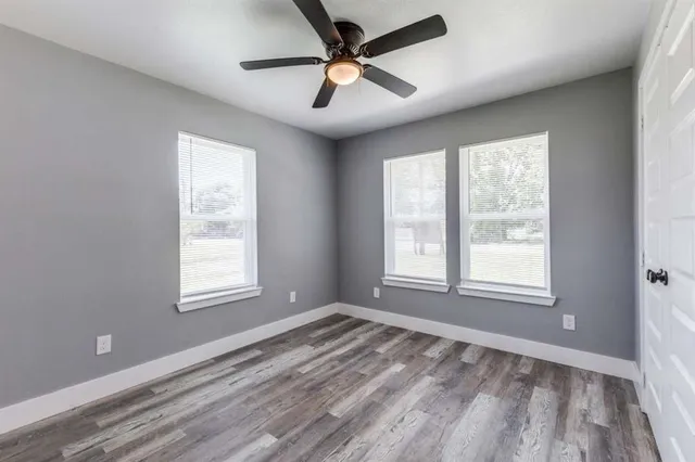a view of empty room with wooden floor and fan
