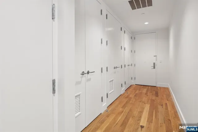 a view of a hallway with wooden floor and a bathroom
