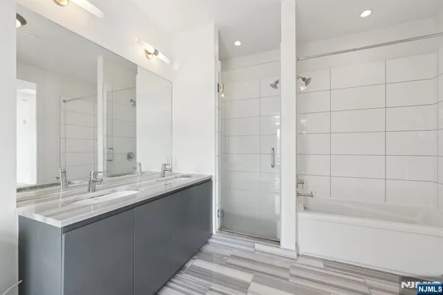 a bathroom with a granite countertop sink mirror and a bathtub