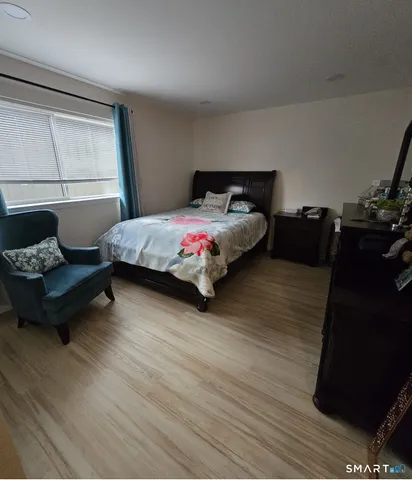 a spacious bedroom with a bed and wooden floor