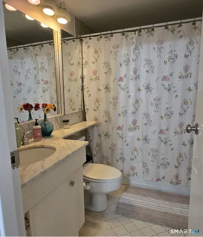 a bathroom with a granite countertop sink and a toilet