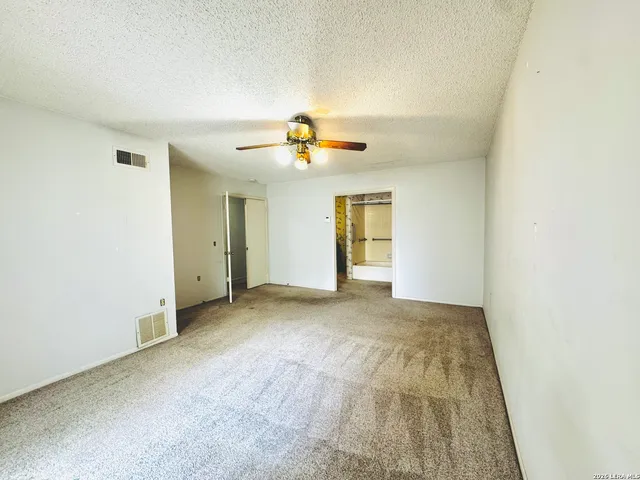 a view of an empty room and chandelier fan