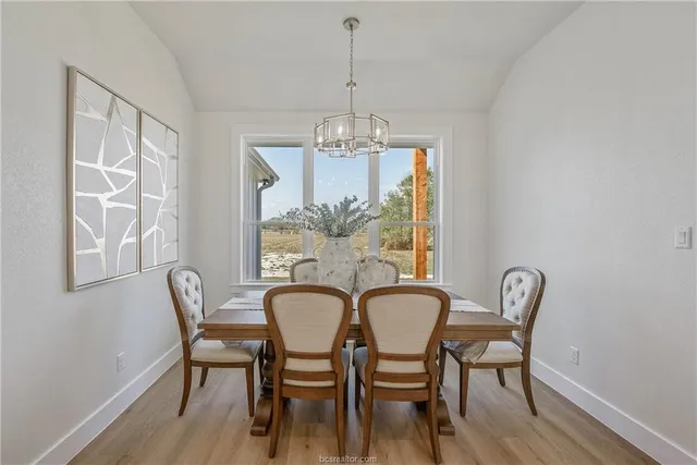 a dining room with furniture a chandelier and wooden floor