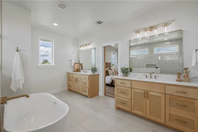 a bathroom with a double vanity sink mirror and bathtub