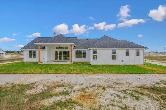 a view of a house with a yard and large tree