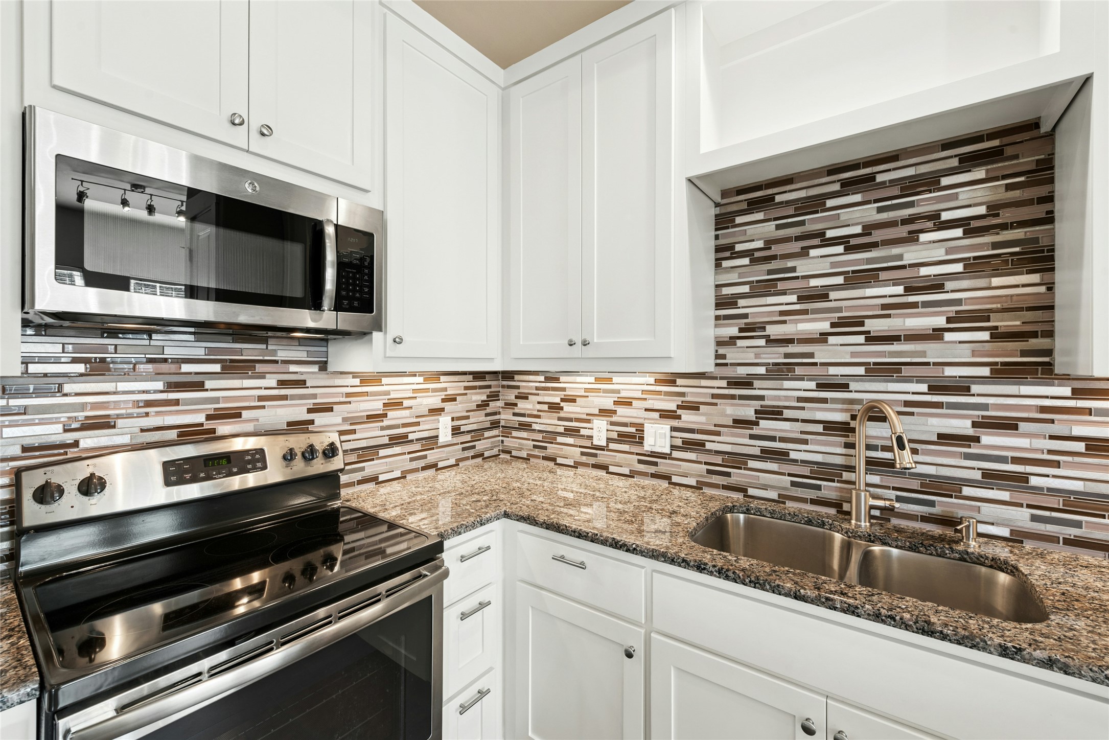 4301 Mansfield Dam Road, Unit 2101 Austin, TX 78734 - Photo 8 of 17 Kitchen featuring stainless steel appliances, white cabinetry, dark stone counters, and backsplash