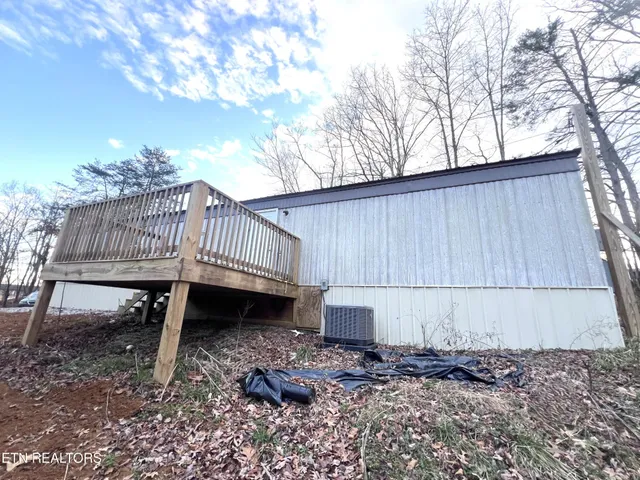 a view of a backyard with a small deck and a barbeque grill with wooden fence