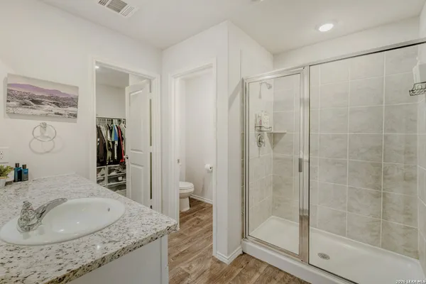 a bathroom with a granite countertop sink a mirror and shower
