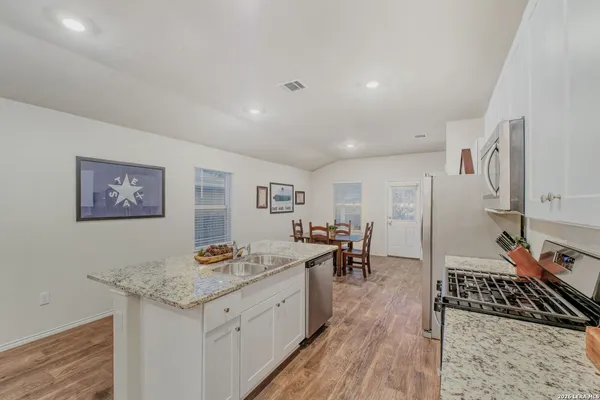 a living room with stainless steel appliances granite countertop furniture and a wooden floor