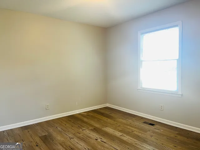 an empty room with wooden floor and a window